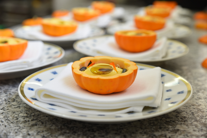 Semifreddo de potimarron servi dans la peau d'un potimarron sur une assiette blanches avec des couronnes bleues.